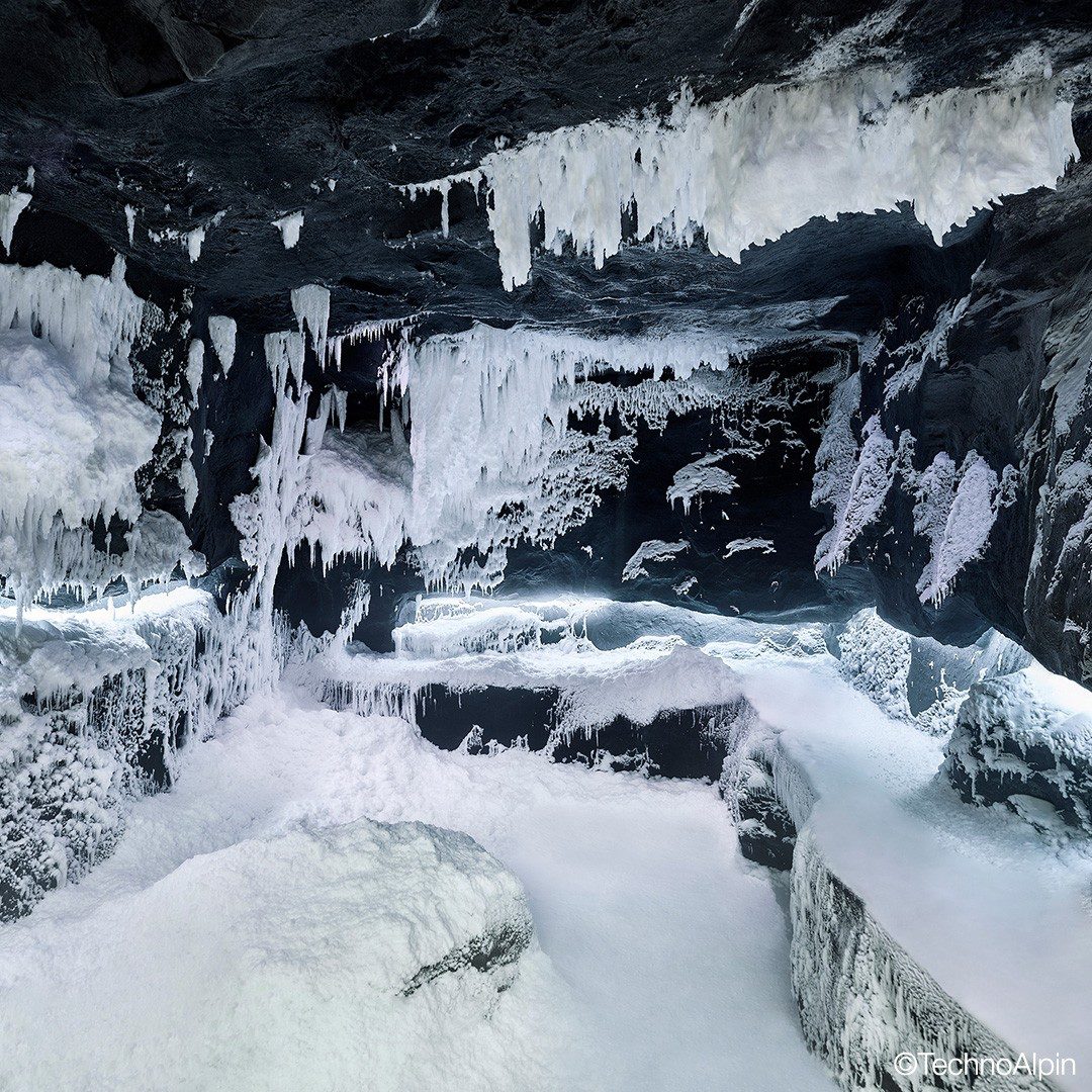 An ice grotto with icicles and snow-covered rock.