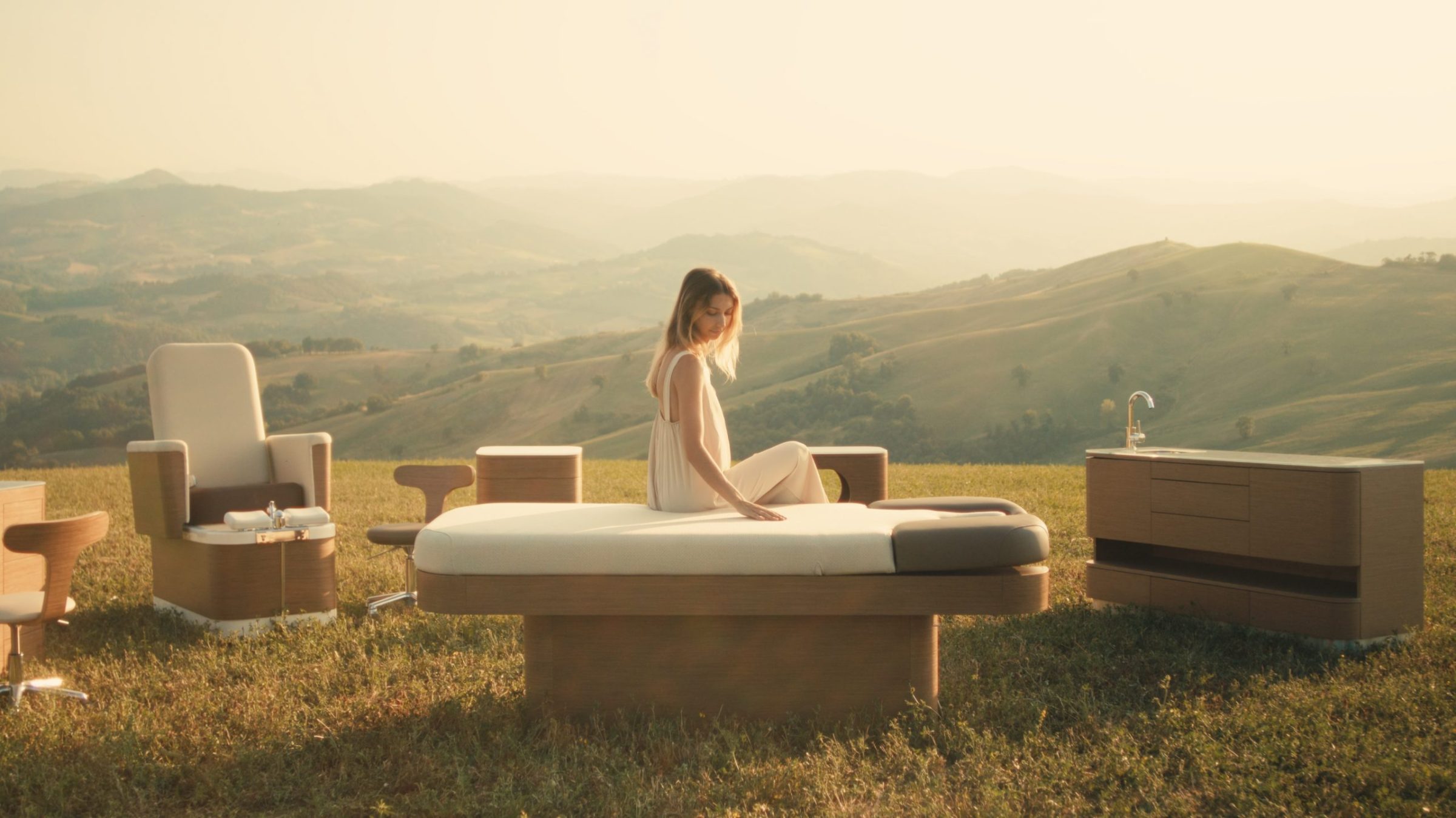 A treatment table and lounge chairs set out on a hillside at sunset.